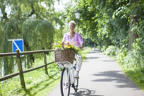 Eine Fahrradfahrerin hat Blumen im Fahrradkorb.