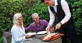 Einem Pärchen wird Flammlachs serviert.