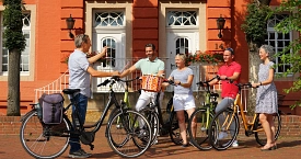 Einer Gruppe von Radfahrern wird gerade von der Reiseleitung das Stadtmuseum gezeigt.