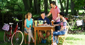 Vier Radfahrer machen im Wald eine Pause und Essen und Trinken dort an einem TIsch.