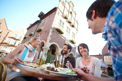 Vier Personen sitzen vor dem Rathaus und Essen