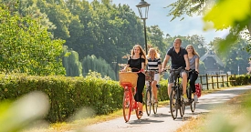 Eine Gruppe von vier Radfahrern radelt entlang des Dortmund-Ems-Kanal-Radweges an der Höltingmühle vorbei.
